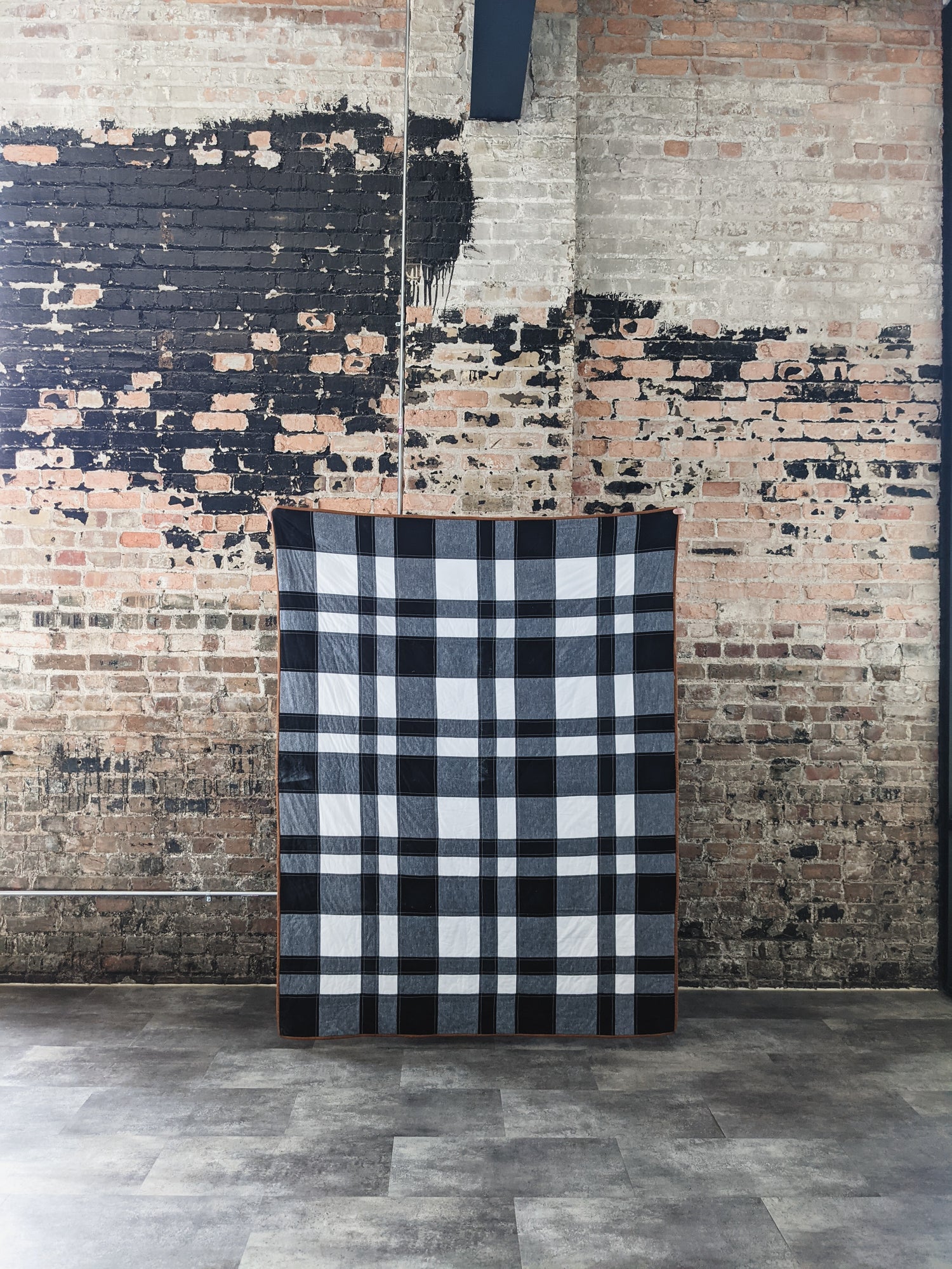 Siracusa Gingham Quilt Pattern against a brick wall